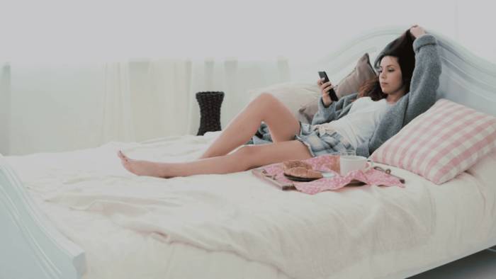 девушка лежит на кровати с телефоном